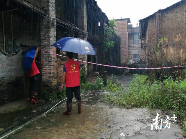 黨群志愿者冒雨拉起警戒線。